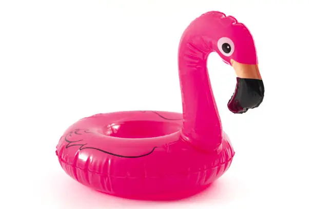 Beach relaxation, the fun and joy of learning to swim and happy summer conceptual idea with inflatable pink lifebuoy in the shape of a flamingo isolated on white background with clipping path cutout