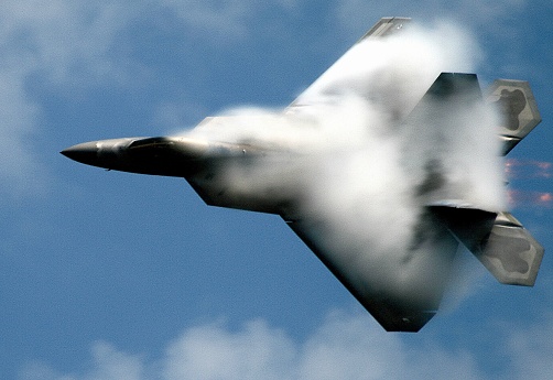 USAF F22 Raptor stealth fighter N. Kingston R.I June 2007. Water vapor get compressed and plumes at high speed.