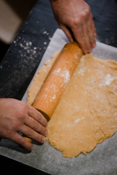 istock baker's hands roll ginger dough on a dark background. Close-up, soft focus. Side view, top view. Copy space 1180241377