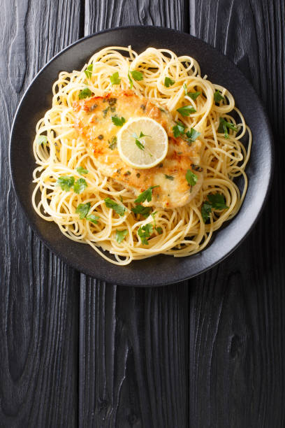 istock Traditional chicken Francaise with spaghetti with lemon sauce close-up on a plate. Vertical top view 1180243408