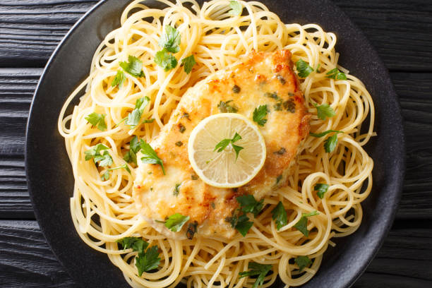 istock cooked chicken Francaise with spaghetti in lemon wine gravy close-up on a plate. Horizontal top view 1180244460