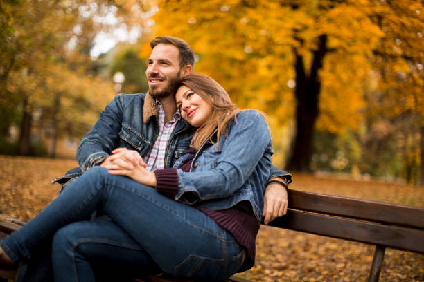 istock Young loving couple on a bench in autumn park 1180244634