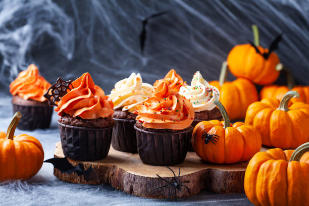 istock Halloween cupcakes and pumpkins on dark background with spooky decoration. Sweets for holiday party. 1180245825