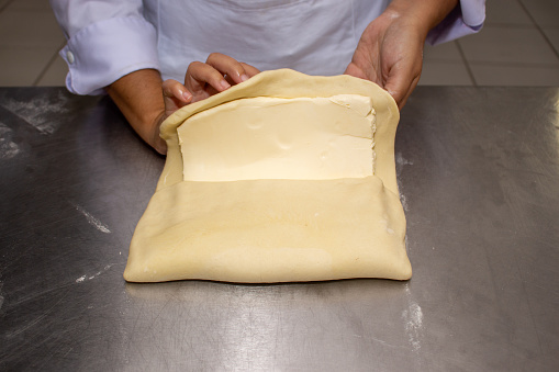 How to make puff pastry. showing the diferent steps of the process. First Open the dough in a square and apply the butter in three quarters of the dough.