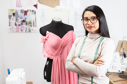 Young Hispanic fashion designer working in her studio - young woman in her small design company
