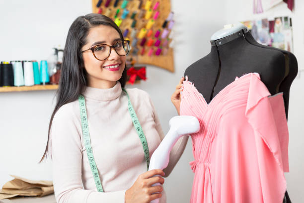 istock Hispanic fashion designer ironing and sewing your creative design in custom studio smiling and looking at the camera - businesswoman woman 1180245919
