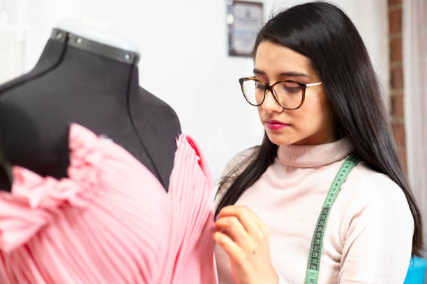istock Hispanic fashion designer in her studio working on her designs taking measurements and adjusting a dress- enterprising woman 1180245921