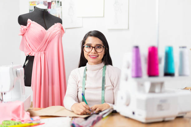 istock Young fashion designer working on her designs in the studio smiling and looking at the camera - enterprising woman 1180246059