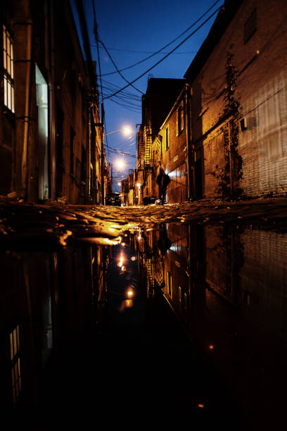 istock Dark alley reflected in puddle - Hoboken, NJ 1180246603