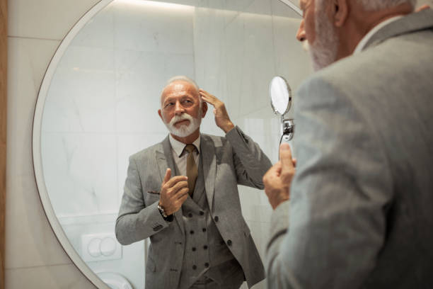 Senior businessman dressing up in bathroom Businessman dressing up in bathroom man adjusting tie stock pictures, royalty-free photos & images