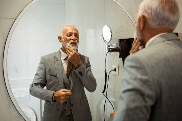 istock Businessman dressing up in bathroom touching his gray beard 1180248332