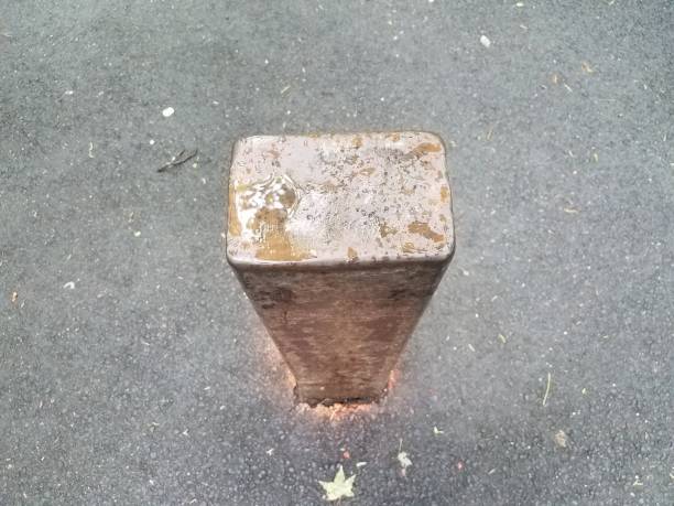 istock brown metal pole or bollard on black asphalt with water 1180250028