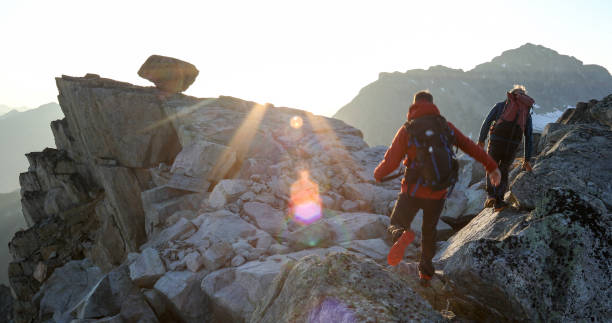 two mountaineers traverse summit ridge at sunrise - achievement mature adult adult mountain range imagens e fotografias de stock