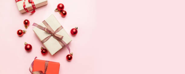 istock Christmas composition with red present box, ribbons, red big and small balls, holiday decorations on pink background. Flat lay, top view, copy space 1180253051