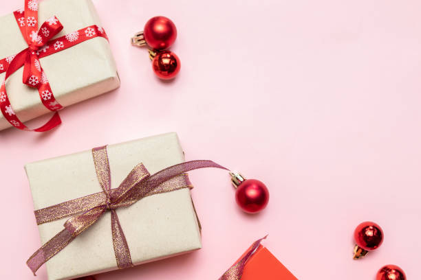 istock Christmas composition with red present box, ribbons, red big and small balls, holiday decorations on pink background. Flat lay, top view, copy space 1180253057