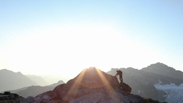 istock Mountaineer crosses summit ridge at sunrise 1180253080