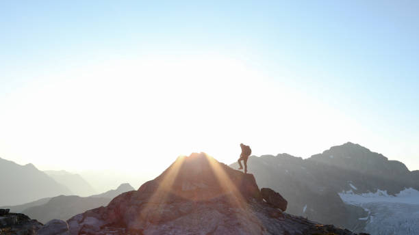 istock Mountaineer crosses summit ridge at sunrise 1180253112