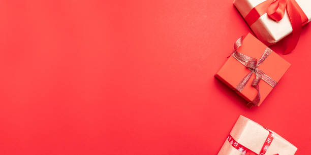 istock Creative gifts or presents boxes with gold bows and star confetti on red background top view. Flat lay composition for birthday, christmas or wedding. 1180253113