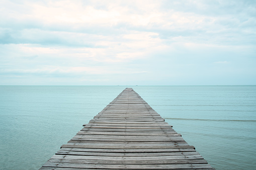 A wooden bridge that stretches out to the sea, seascape view with cloudy sky