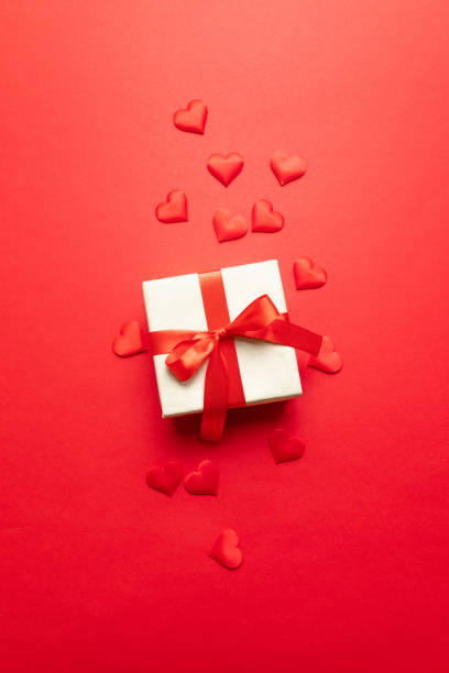 istock Valentines day concept. Red hearts, kraft surprise box with bow on a red background. Flat lay, top view, copy space Minimal concept for birthday, mother day or wedding. 1180253442