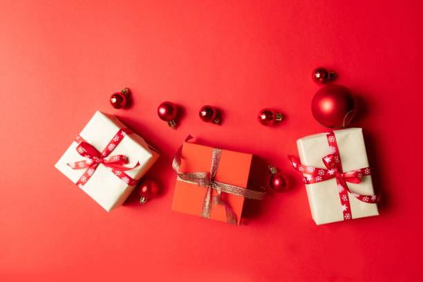 istock Christmas composition with red present box, ribbons, red big and small balls, holiday decorations on red background. Winter, new year concept. Flat lay, top view, copy space 1180253459