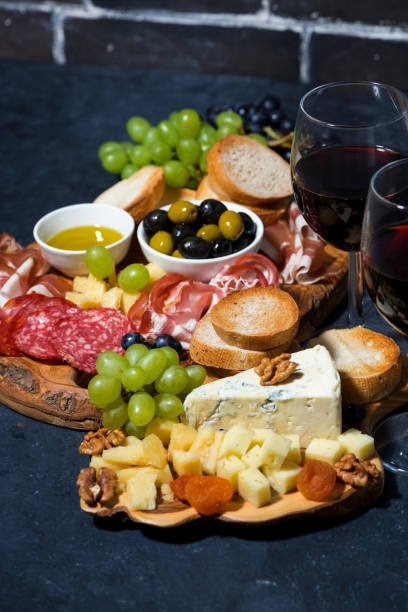 istock cheese platter, bread, fruit and cold cuts to wine on dark background, vertical 1180254119