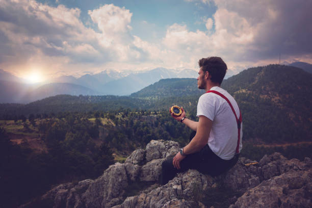 Hiker sitting on top of the mountain and trying to find his way.
