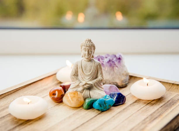 All seven chakra colors crystals stones around sitting Buddha figurine on natural wooden tray. Balance and calm energy flow in home concept. All seven red, orange, green, blue, purple chakra colors crystals stones around sitting Buddha figurine on natural wooden tray. Balance and calm energy flow in home concept. chakra recovery energy gem stock pictures, royalty-free photos & images