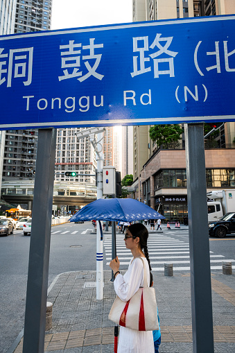A woman waits to cross the street at Tonggu Road near High-Tech Park in Shenzhen, China. (September 6, 2019)
