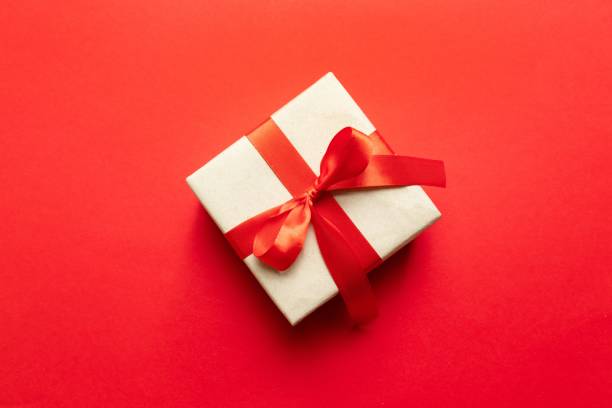 Celebration party background with gift box and red bow on red background