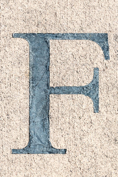 A black capital letter F in a concrete sidewalk.