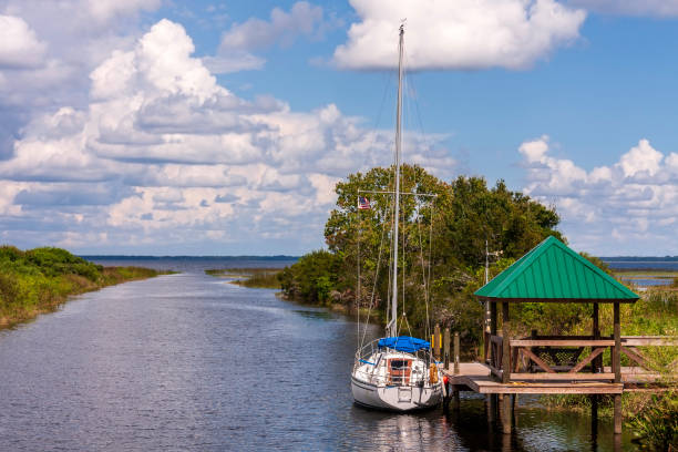 Sailboat moored at a dock with a sitting area under a gazebo on an outlet to the lake between St Cloud and Kissimmee, Florida stock photo