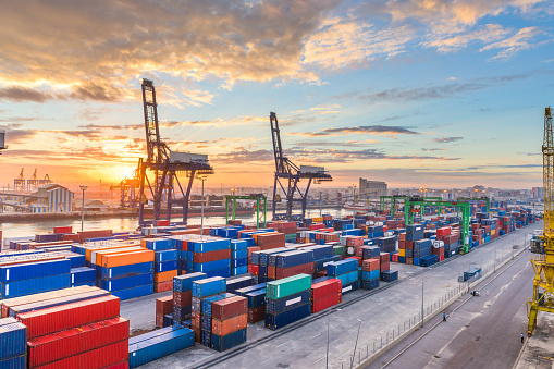 Gantry cranes move cargo containers in a busy port.