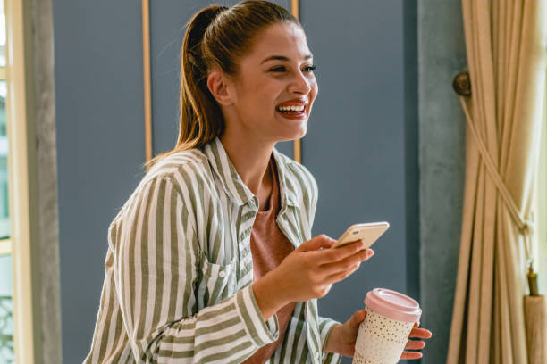 istock Young woman holding phone and coffee 1180263843
