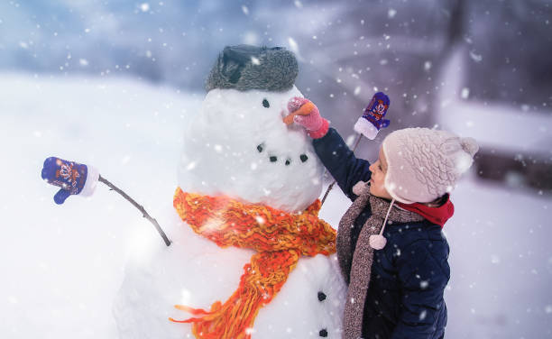 Child Winter Outdoor Fun Child sculpts a snowman in a park snowman stock pictures, royalty-free photos & images