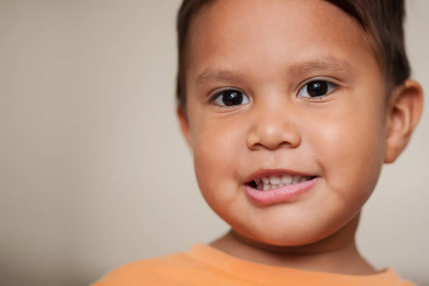 A three year old boy with a look that can be described as amazed, uncertain, or hesitant and with a crooked smile as if he got away with something he did.
