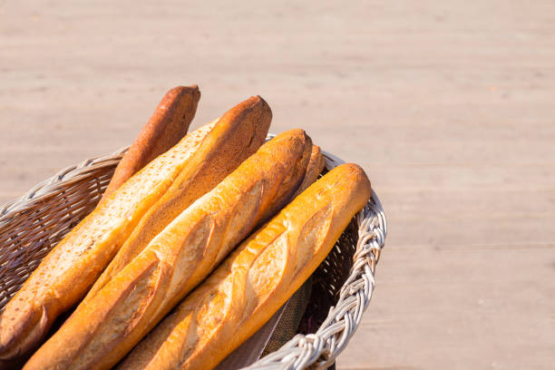 French baguette in rustic wooden basket on brown background