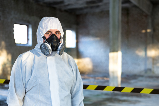 A man is dressed in a chemical protective overalls and a half mask with air filters and safety glasses.