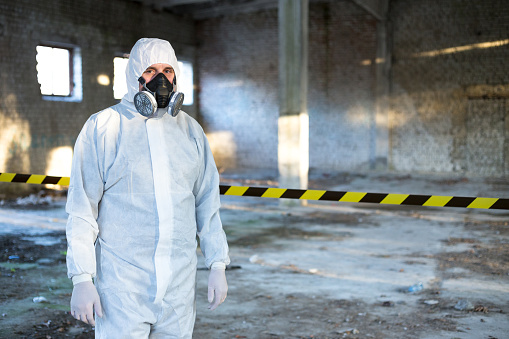 A man is dressed in a chemical protective overalls and a half mask with air filters and safety glasses.