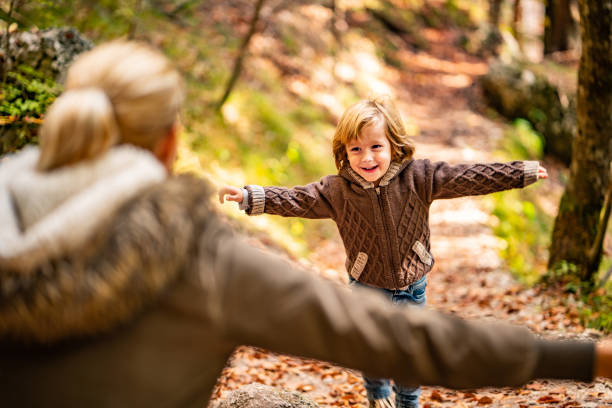 Small cute boy running to mothers hug in nature