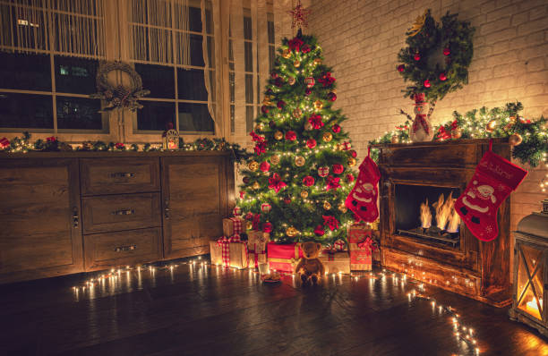 Decorated Christmas Tree Near Fireplace at Home Christmas tree near fireplace in decorated living room floral garland photos stock pictures, royalty-free photos & images