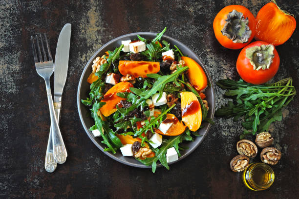 Salad with persimmon, arugula, white cheese and nuts. Keto diet. Keto lunch idea. Pegan diet. stock photo