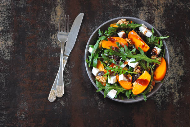 istock Salad with persimmon, arugula, white cheese and nuts. Keto diet. Keto lunch idea. Pegan diet. 1180277761