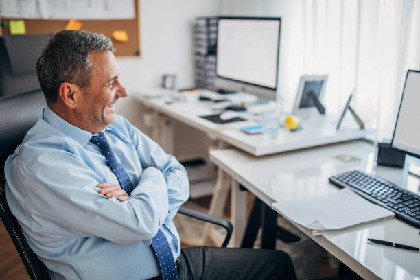 istock Cheerful senior businessman sitting at the office 1180278151