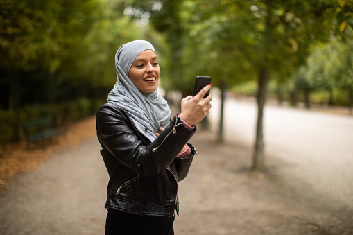 Young muslim woman walking in city park