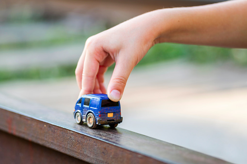 Children kid playing blue color car toy. Child hand playing with car.