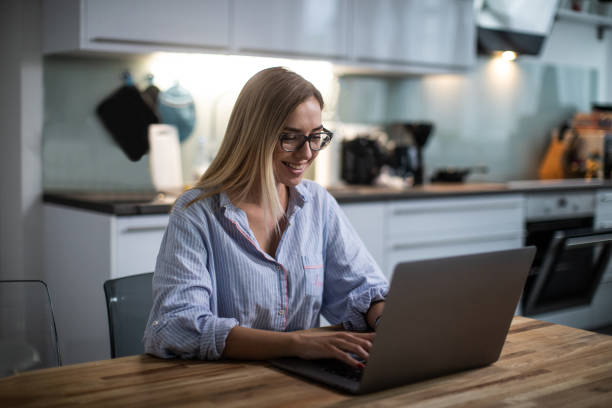 istock Woman with laptop sitting at kitchen table 1180281938