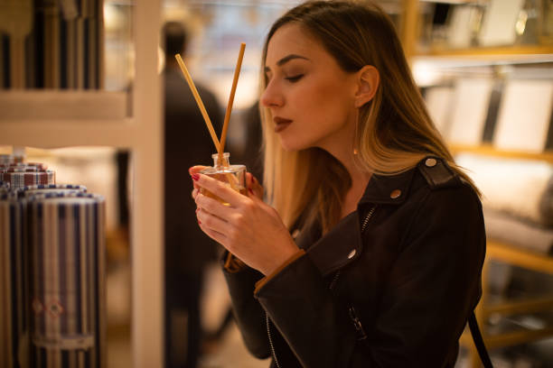 belle femme smeling parfum au magasin - parfum photos et images de collection