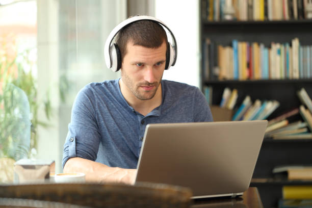 istock Adult man wearing headphones using a laptop 1180289750