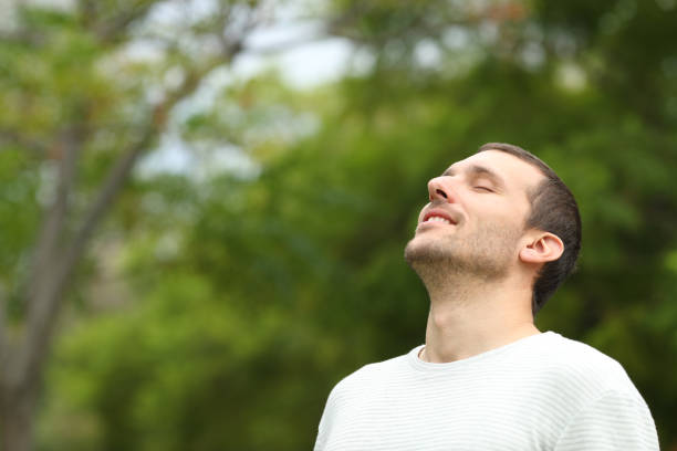 istock Happy man breathing deeply fresh air in a forest 1180290267